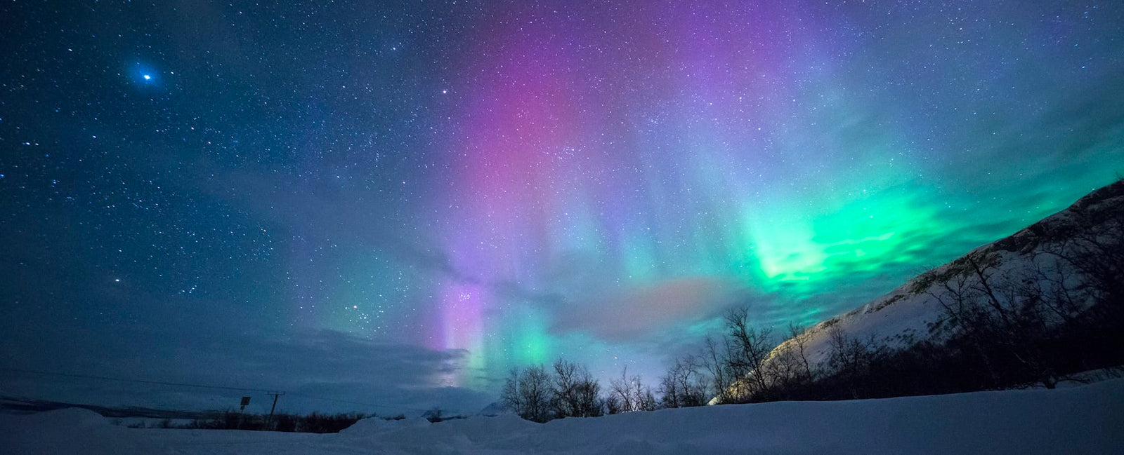 Auroras boreais sobre as montanhas nevadas de Tromsø, na Noruega — o universo nórdico e romântico de Northern Love de Frédéric Malle na Olara