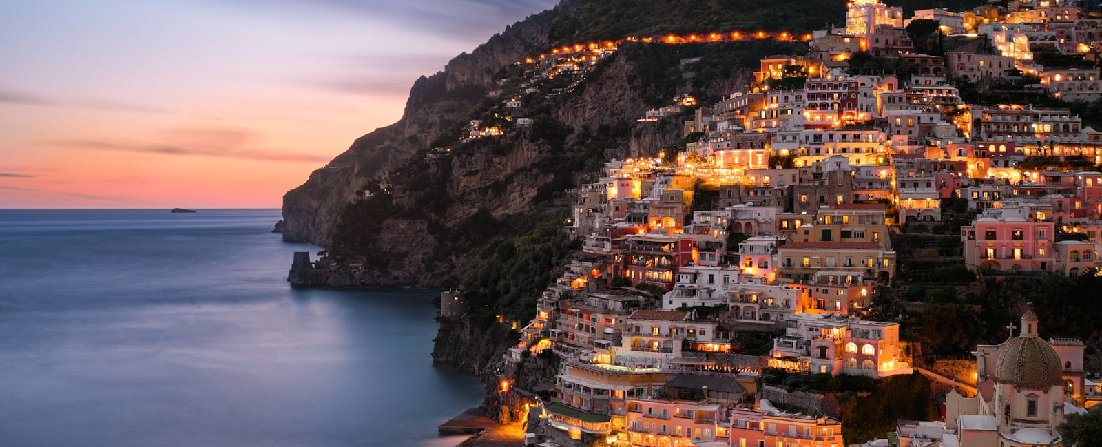 Positano at dusk on the Amalfi coast — the Mediterranean summer of Dolce & Gabbana Light Blue at Olara