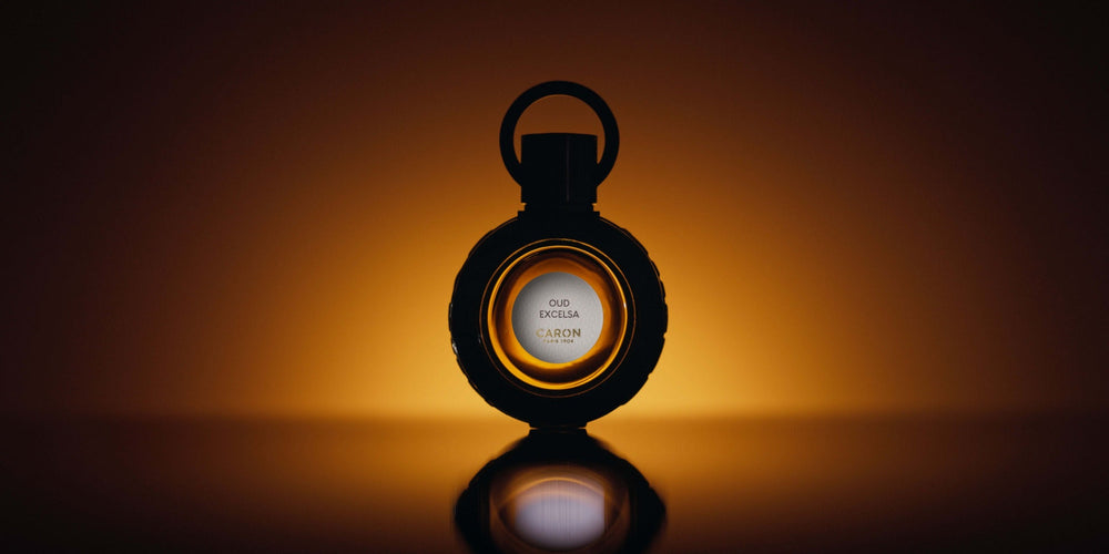 Le flacon d’Oud Excelsa en contre-jour sur fond ambré