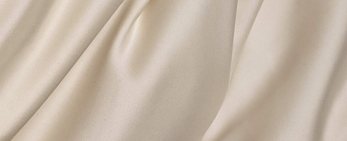 Draped cream satin with luminous highlights — the couture spirit of the Puig group houses, Jean Paul Gaultier, Nina Ricci and Carolina Herrera, at Olara perfumery