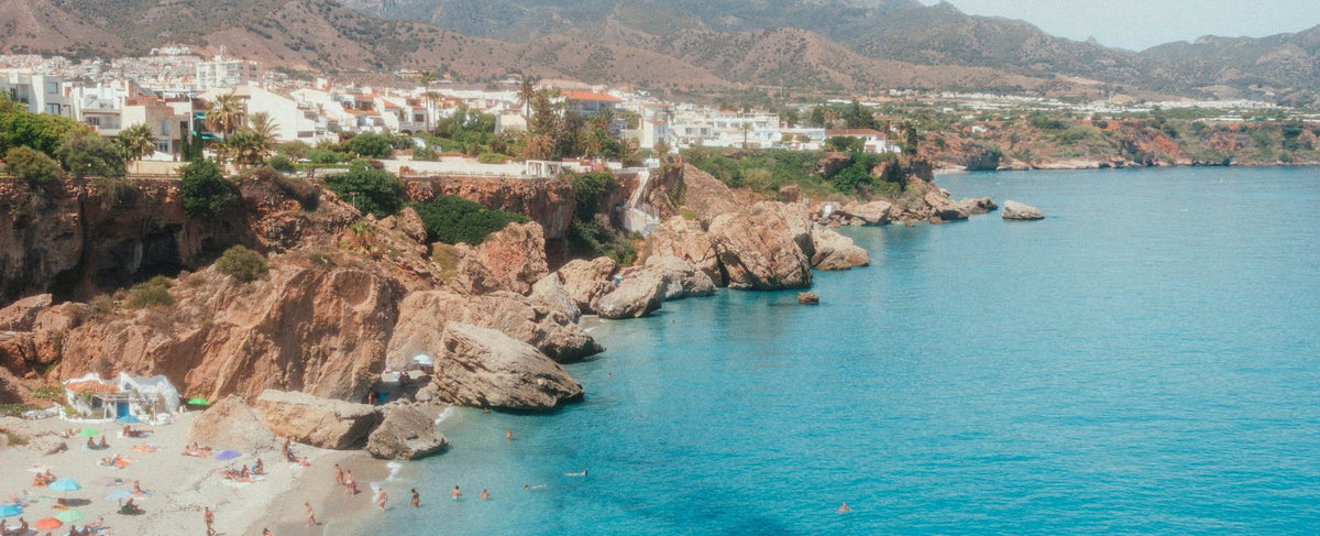 Crique méditerranéenne de Nerja près de Málaga, village blanc au loin — l'univers andalou d'Antonio Banderas et de Colonia Essenza d'Acqua di Parma, par la parfumerie Olara