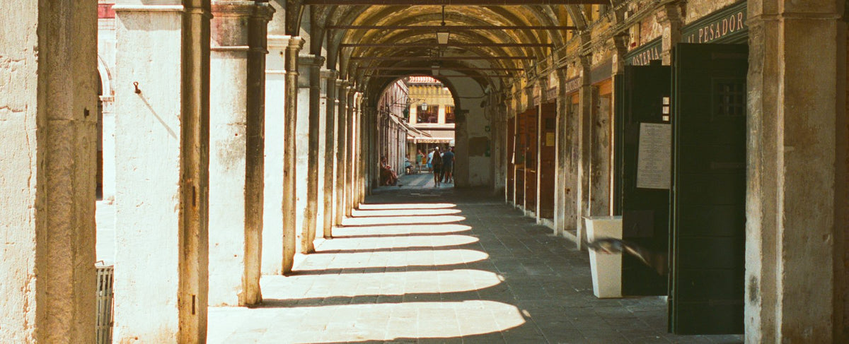 Arcades de pierre italiennes baignées de lumière du matin — l'élégance d'Acqua di Parma et l'univers généreux d'Omar Sy, par la parfumerie Olara