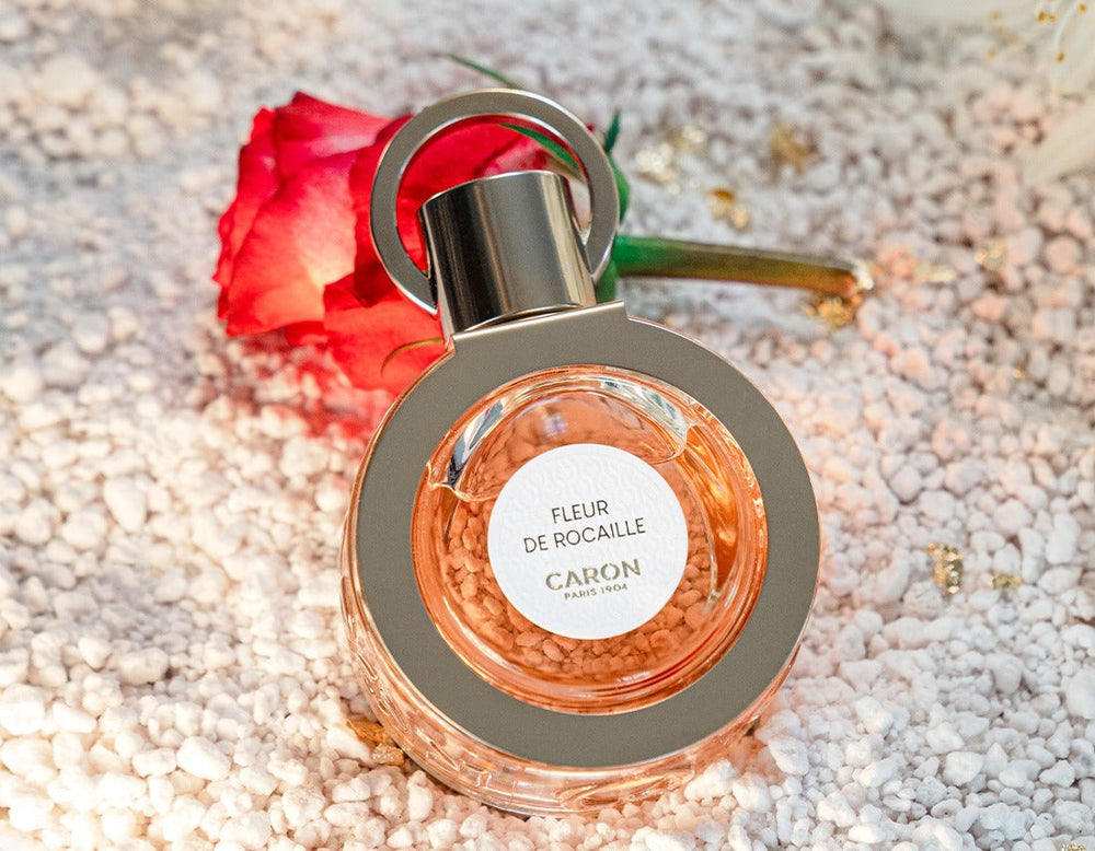 Le flacon de Fleur de Rocaille posé près d’une rose rouge
