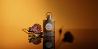 Le flacon de Santal Précieux et une rose sur fond ambré